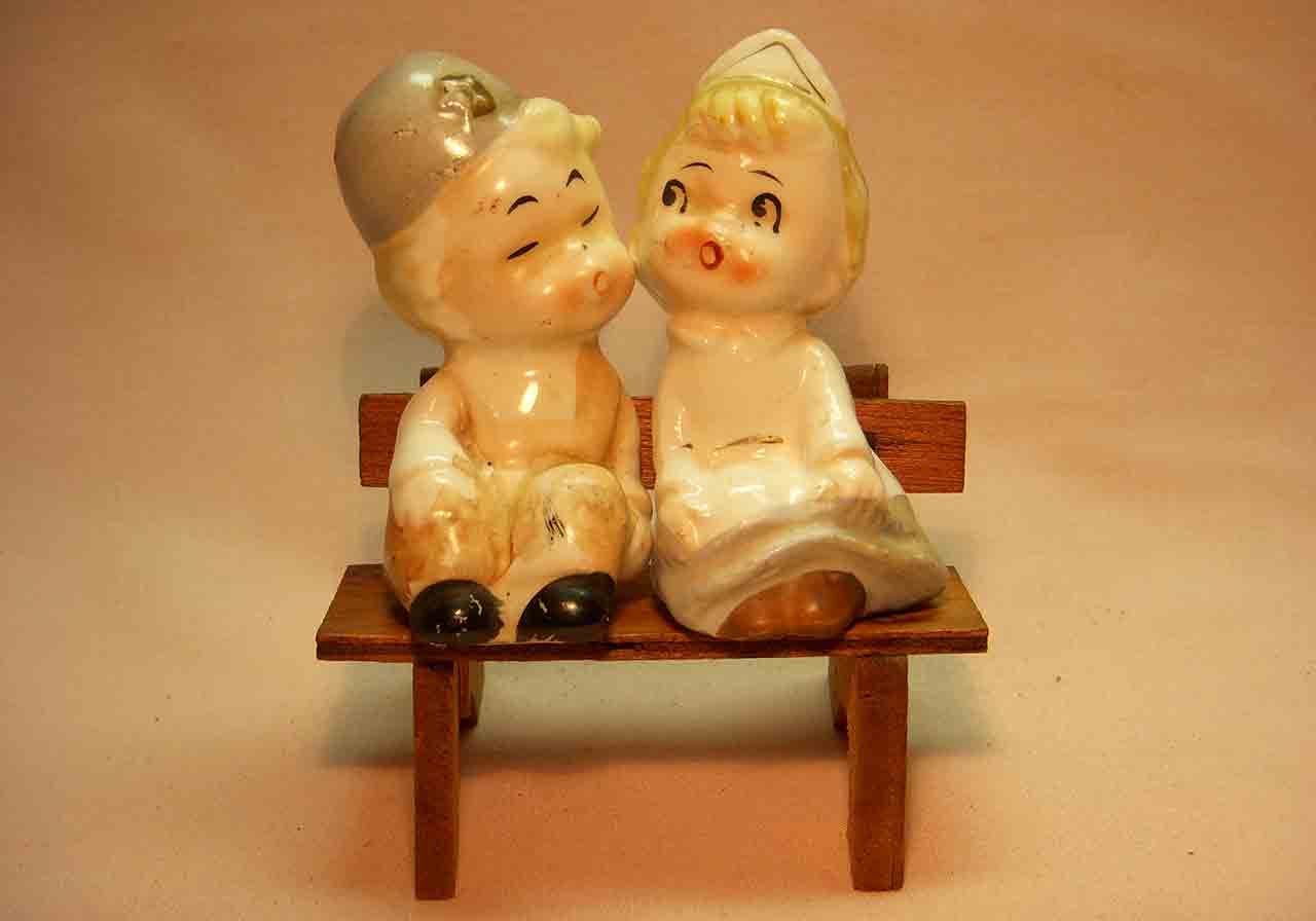 Little boy and nurse girl sitting on wooden bench salt and pepper shaker